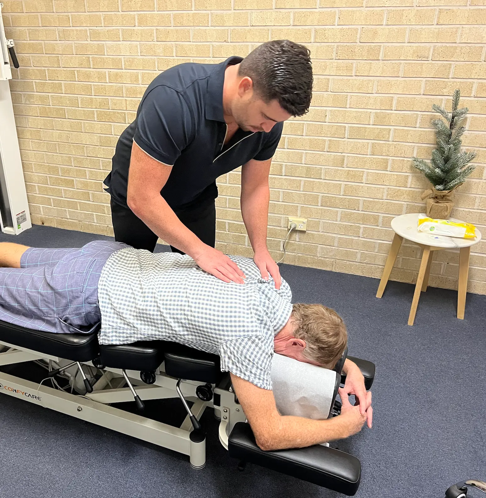 Kurt assessing a patient on the treatment table at Baseline Chiro